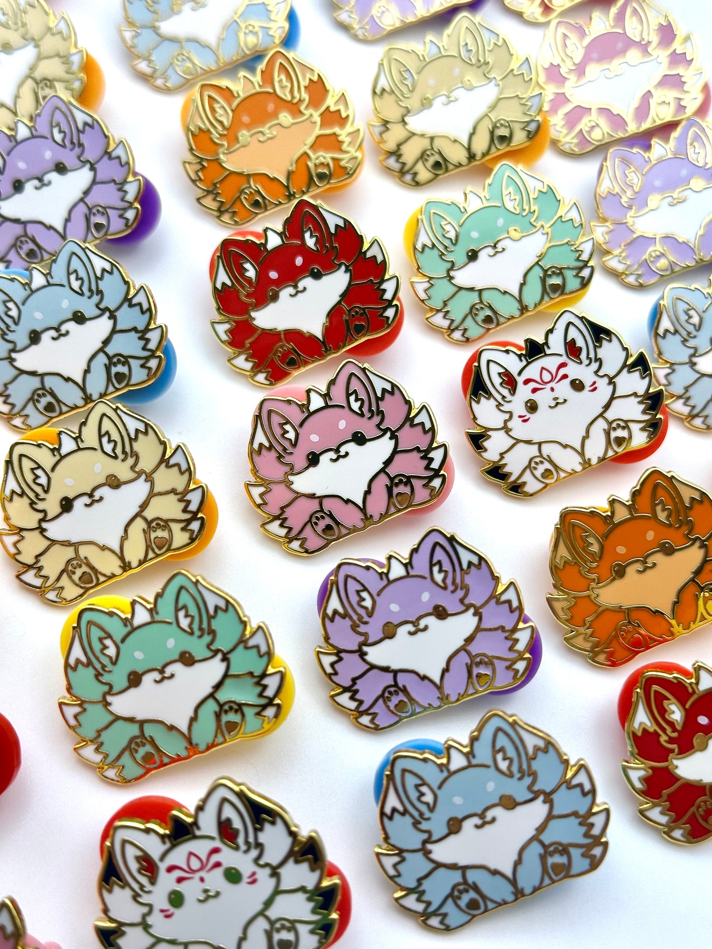1" kitsune mini pins ranging in different colors lined up in a pattern