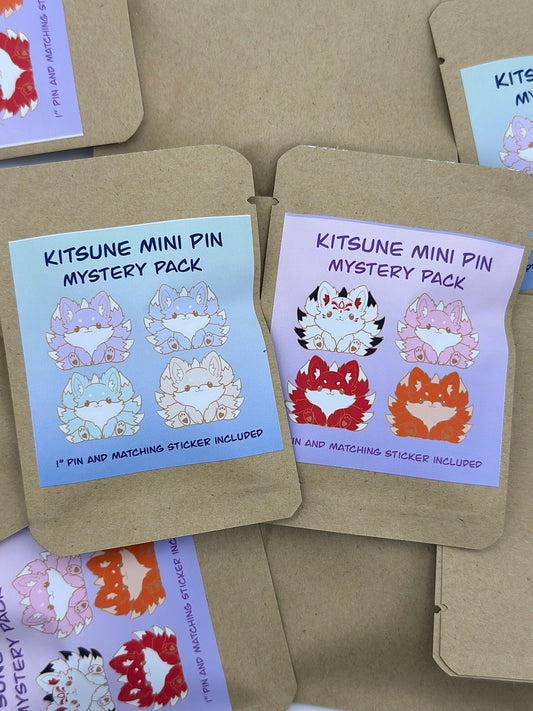 Packaging for Kitsune Mini Pin Mystery Pack showing various designs of fox face pins with matching stickers displayed behind them.