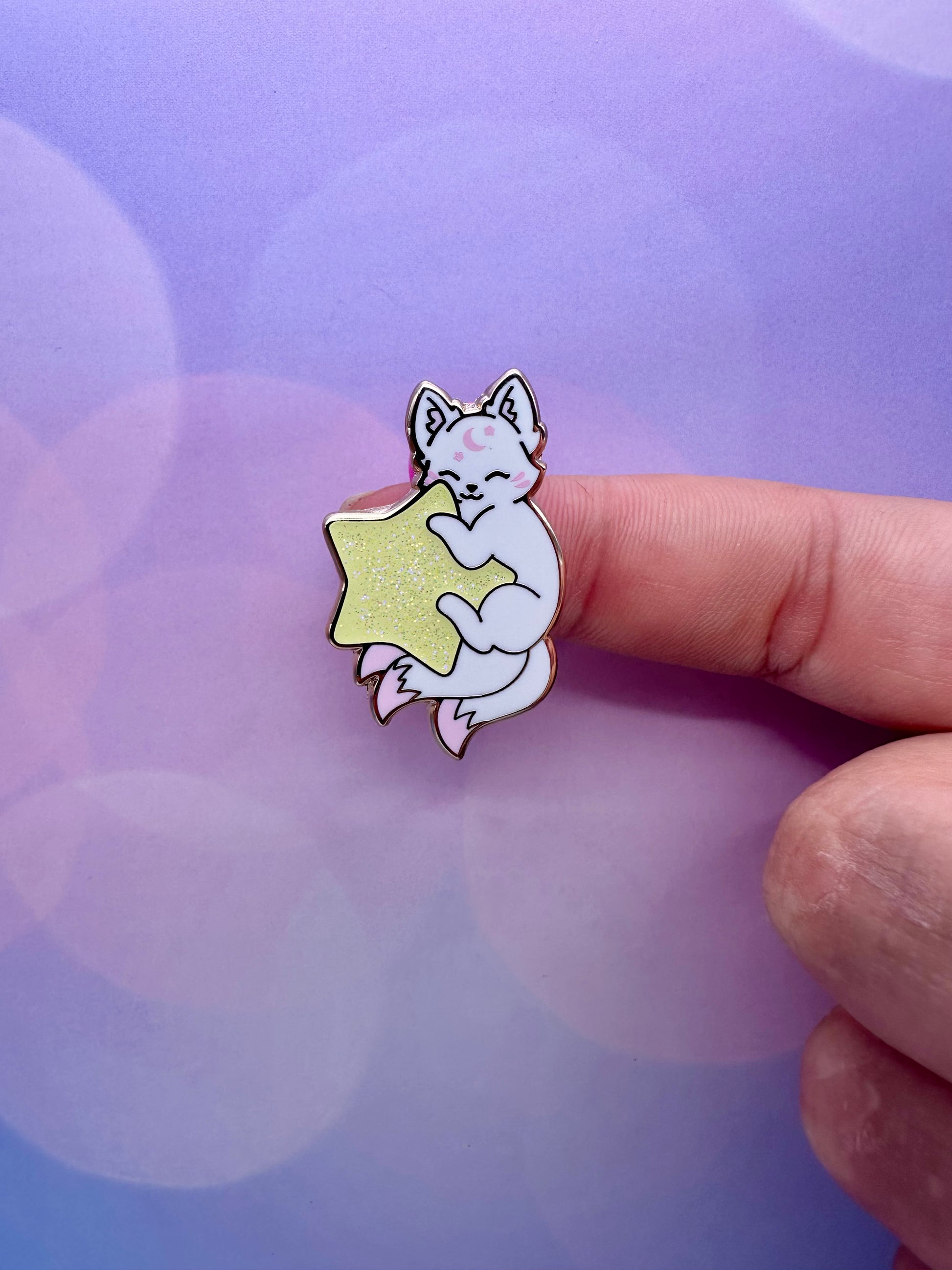 Cute white kitsune enamel pin hugging a glittery yellow star with pastel pink accents and gold metal details