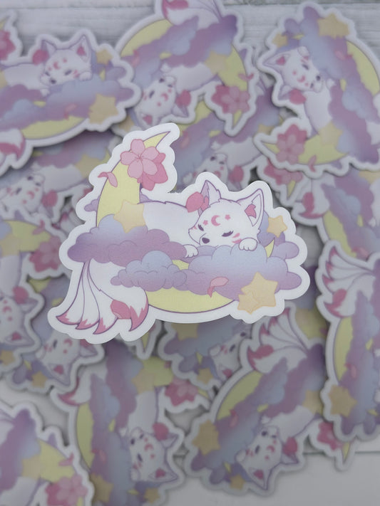 Cute pastel kitsune sleeping on lavender clouds beneath a crescent moon surrounded by stars and pink sakura petals