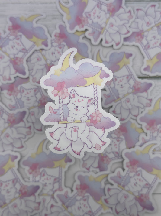 Cute pastel kitsune sitting on a swing suspended from clouds and a crescent moon with cherry blossoms and stars