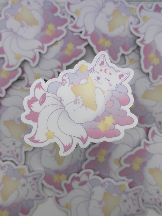 Pastel kitsune lying on fluffy clouds while hugging a glowing yellow star surrounded by small stars and petals