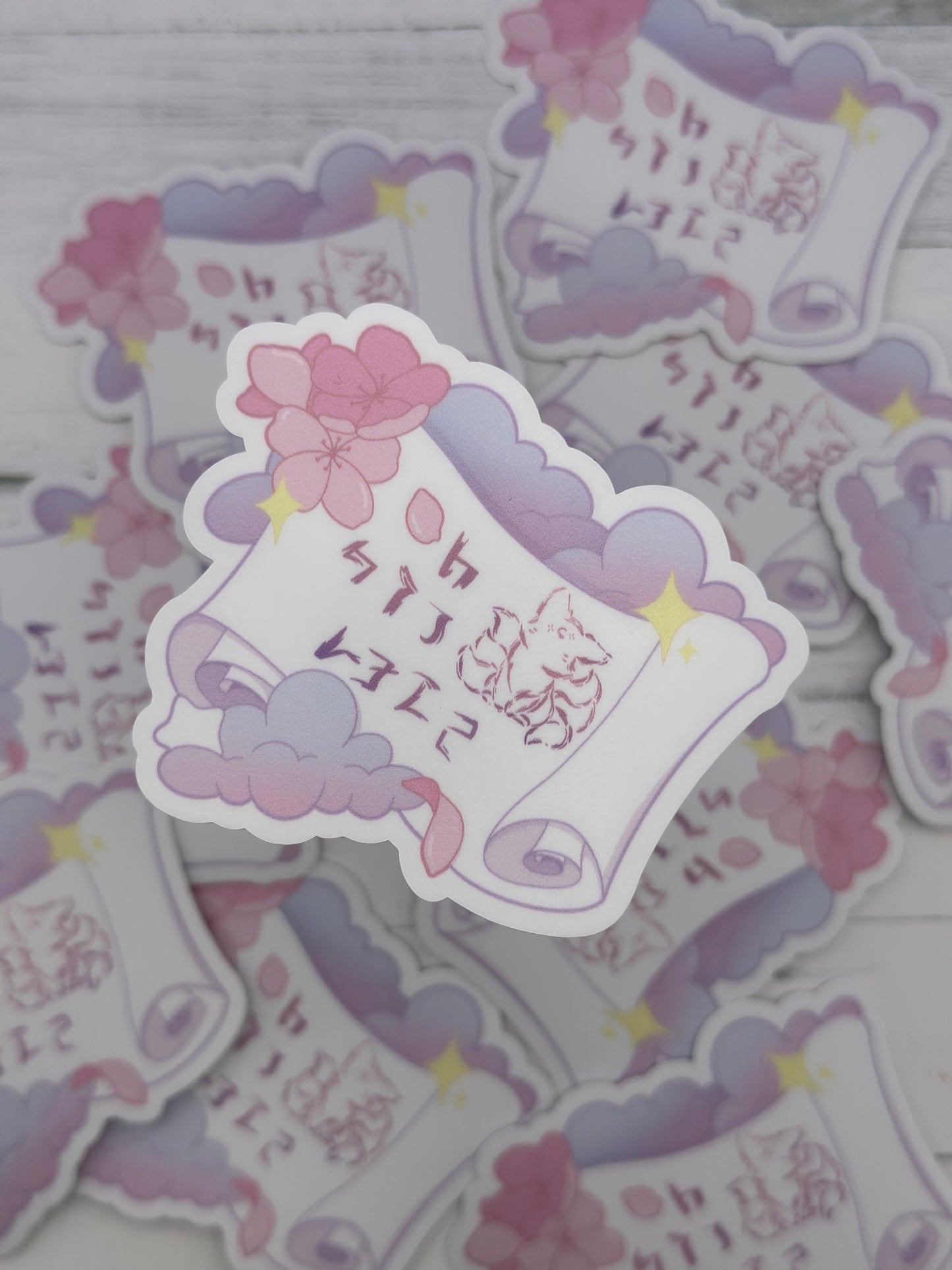 Pastel fantasy scroll sticker featuring stylized kitsune-inspired runes on a curled parchment surrounded by lavender clouds, cherry blossoms, and glowing stars