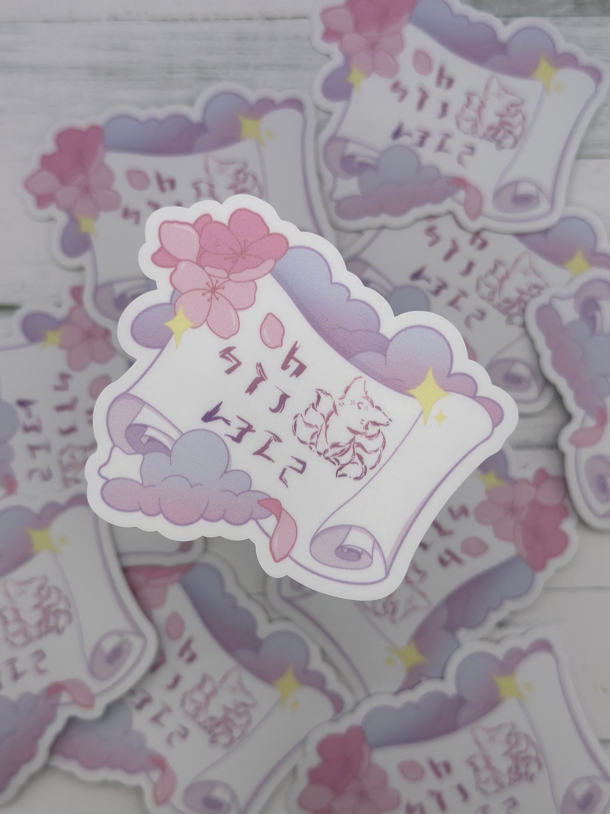 Pastel fantasy scroll sticker featuring stylized kitsune-inspired runes on a curled parchment surrounded by lavender clouds, cherry blossoms, and glowing stars