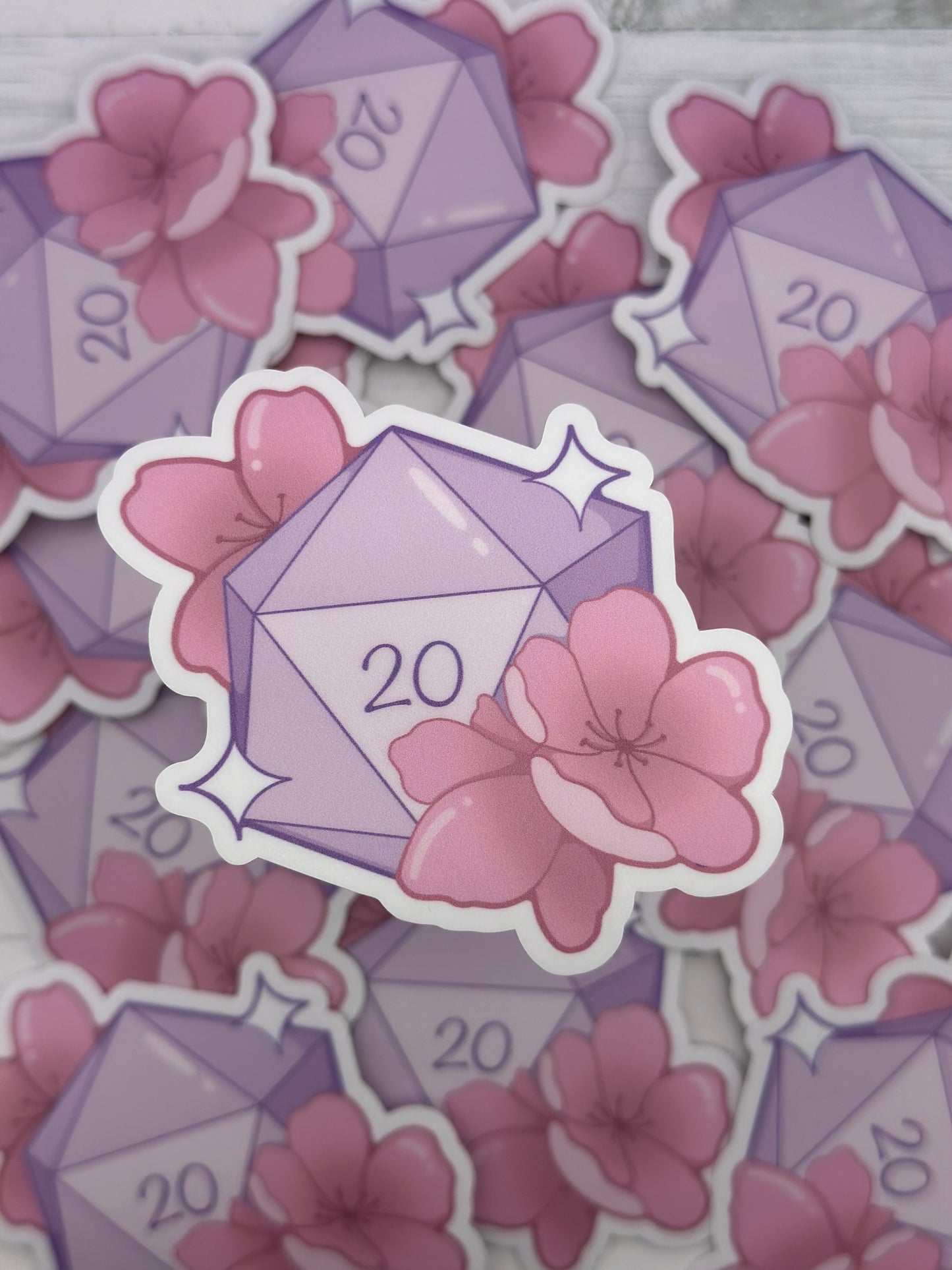 Lavender twenty-sided dice sticker decorated with pink sakura flowers and sparkles in a soft pastel style