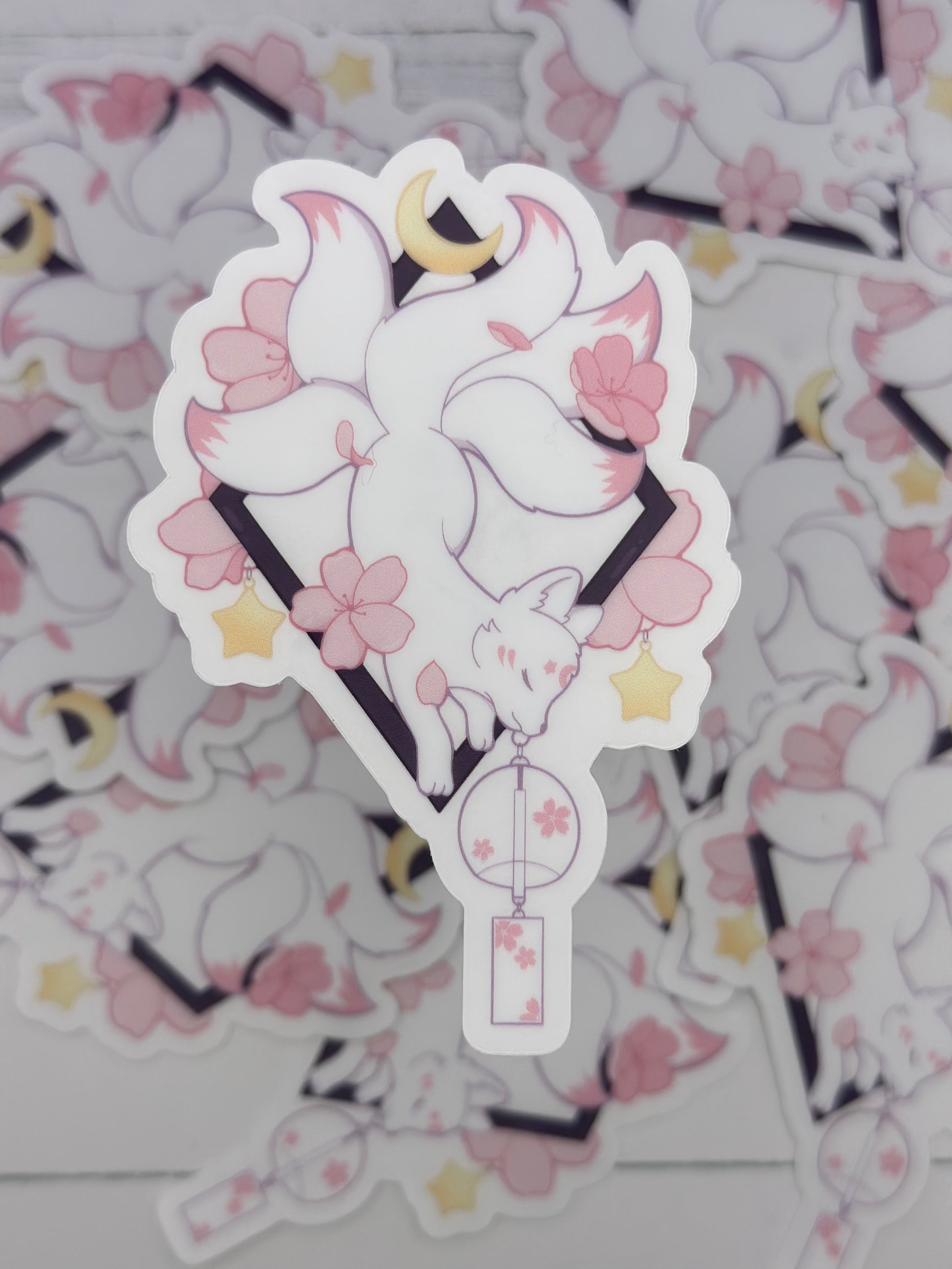 Elegant kitsune sticker featuring flowing white tails, cherry blossoms, stars, and a hanging floral lantern beneath a crescent moon
