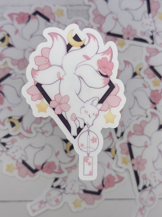 Elegant kitsune sticker featuring flowing white tails, cherry blossoms, stars, and a hanging floral lantern beneath a crescent moon