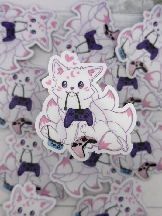 Cute pastel kitsune surrounded by colorful game controllers while holding a purple controller cord in its mouth