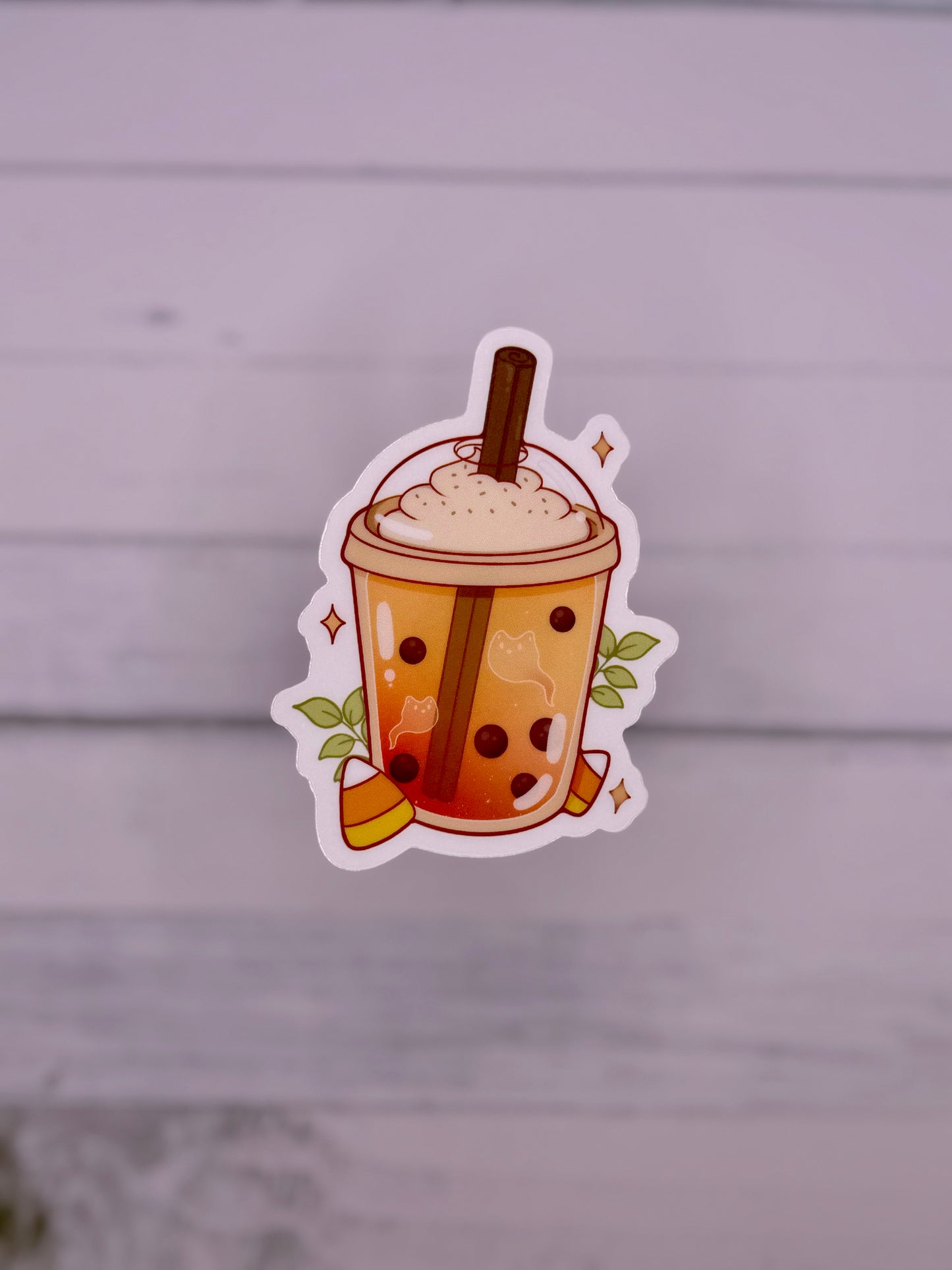 Cute Halloween themed bubble tea sticker featuring an orange milk tea with ghost shapes, boba pearls, whipped topping, cinnamon stick, candy corn, and sparkles