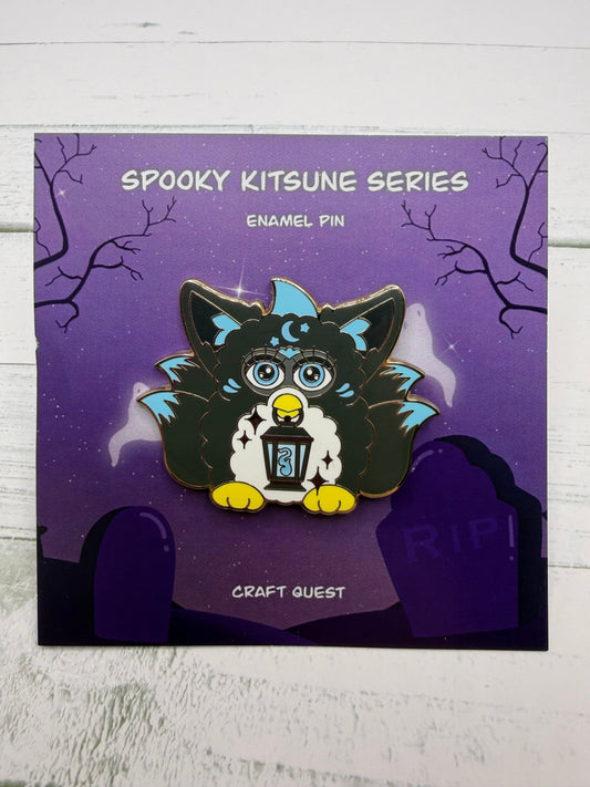Black and blue retro electronic pet inspired kitsune enamel pin holding a lantern on a purple spooky graveyard backing card