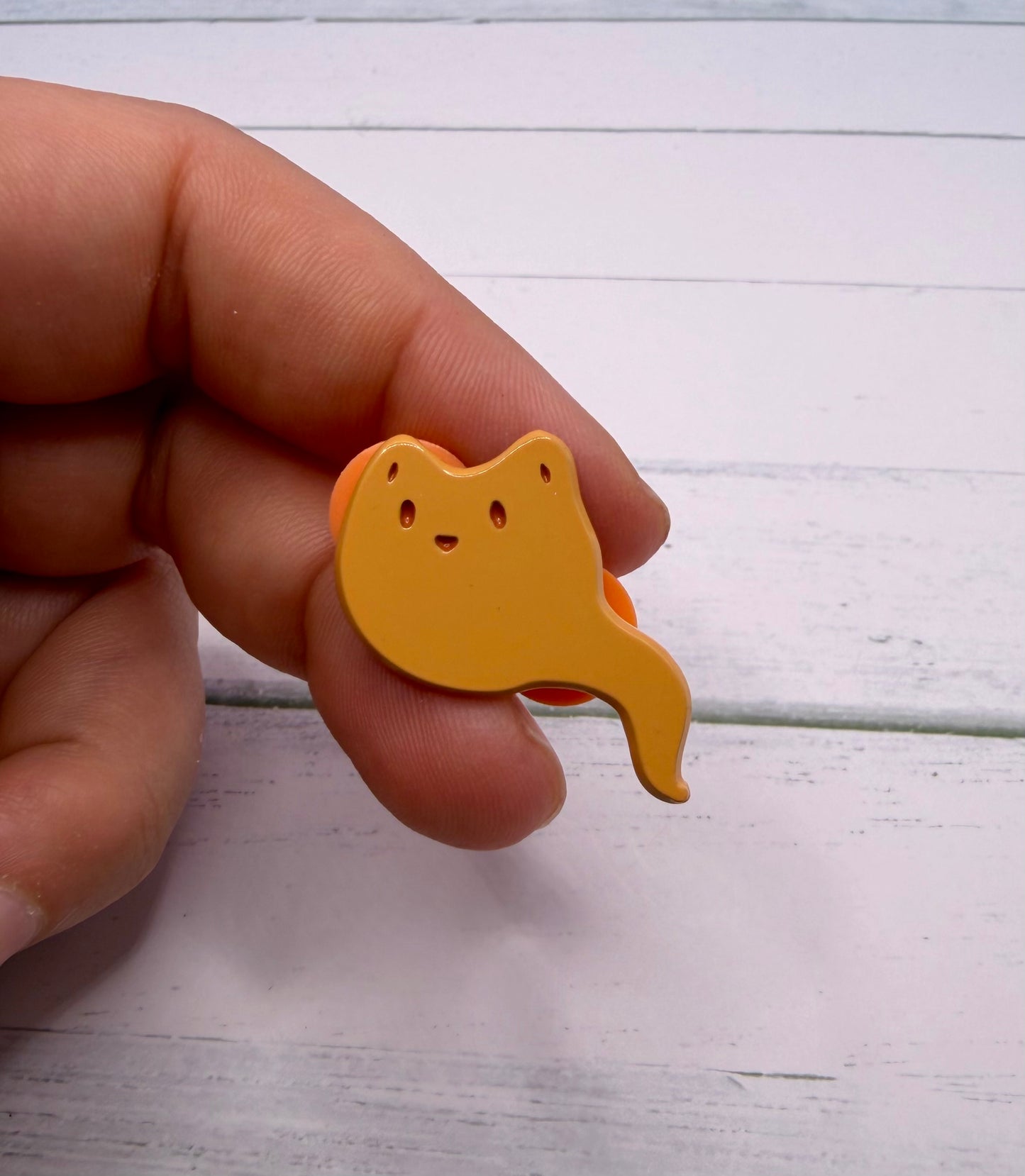 Orange ghost fox enamel pin with a curved ghost tail